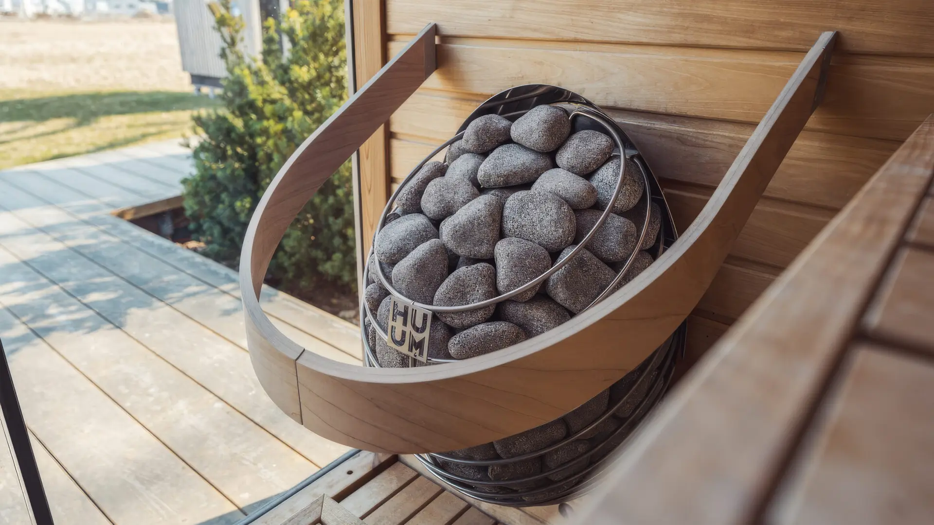 HUUM Drop electric sauna heater filled with grey stones inside a light cedar-lined sauna interior